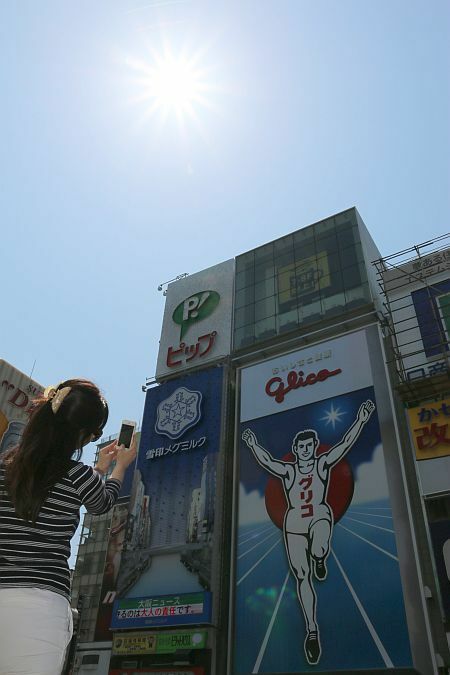 [写真]青空が広がり朝から強い日差しの大阪・道頓堀周辺。記念撮影を楽しむ人も＝30日午前11時ごろ、大阪市中央区で
