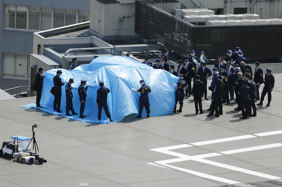 落下したドローンをブルーシートで囲う＝2015年4月22日（写真：ロイター/アフロ）