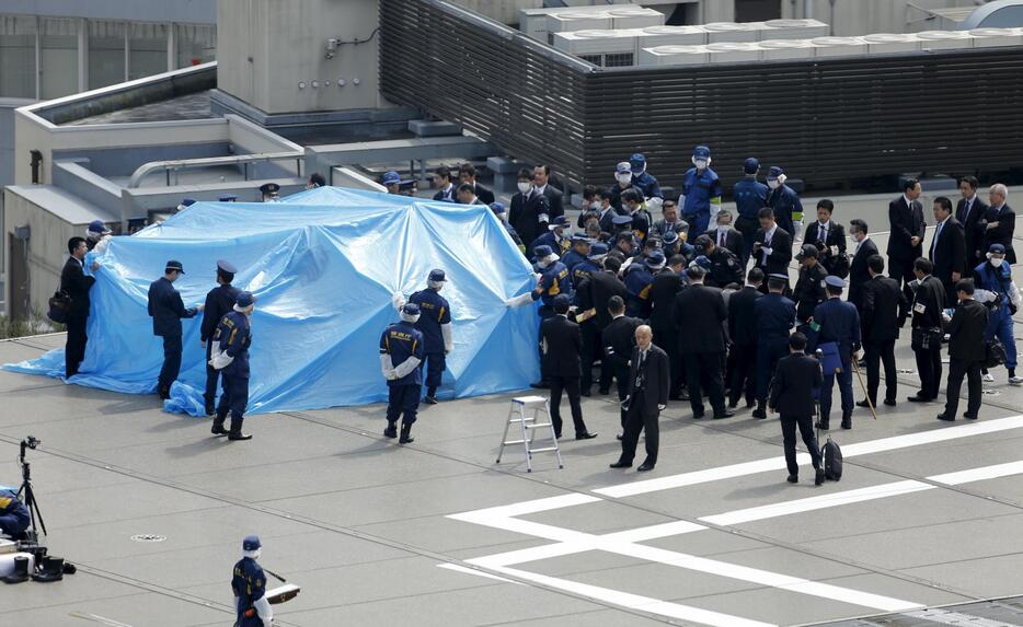 ブルーシートのまわりにあつまる捜査員＝2015年4月22日（写真：ロイター/アフロ）