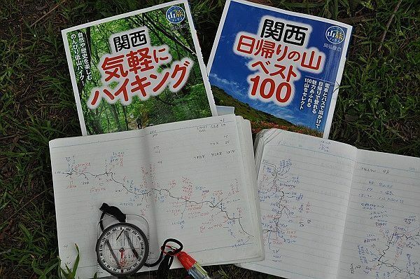 [写真]岡弘さんの新刊「関西気軽にハイキング」「関西日帰りの山ベスト100」と取材ノート。登山コースの情報を現場で丹念に書き込んだノートから労作ガイドブックが生まれた