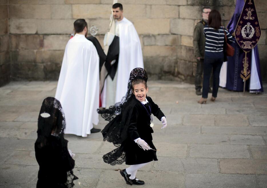 聖週間（Holy Week）の行列へ参加する前に遊ぶ女の子（ロイター/アフロ）