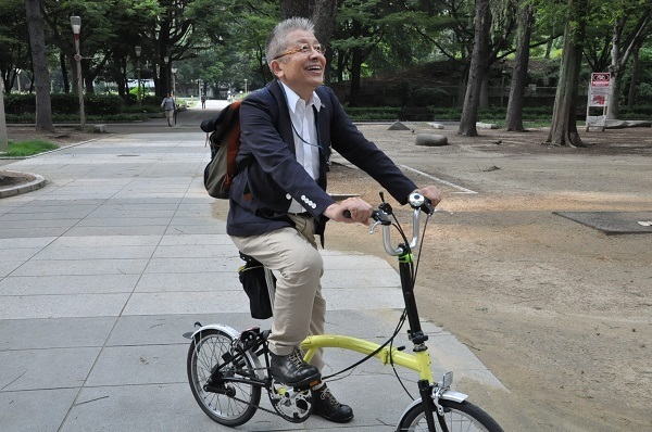 [写真]折り畳み式自転車で取材する竹原信夫さん。東大阪の町工場街も自転車で駆け巡る