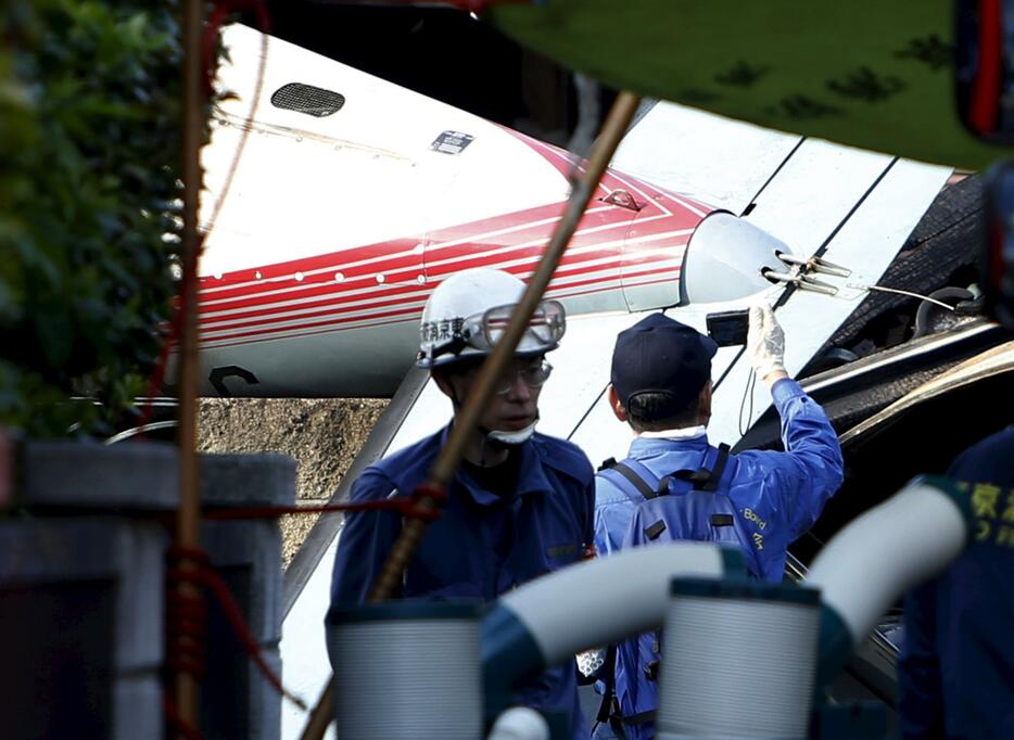 墜落した機体の写真を撮る運輸安全委員会の職員＝2015年7月26日（写真：ロイター/アフロ）