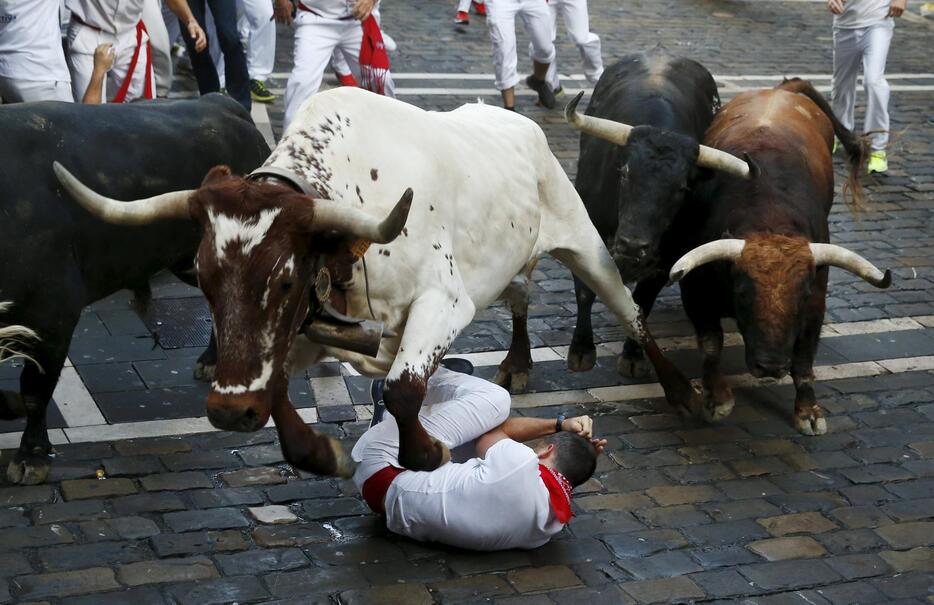 倒れた人を飛び越える牛＝2015年7月7日（写真：ロイター/アフロ）