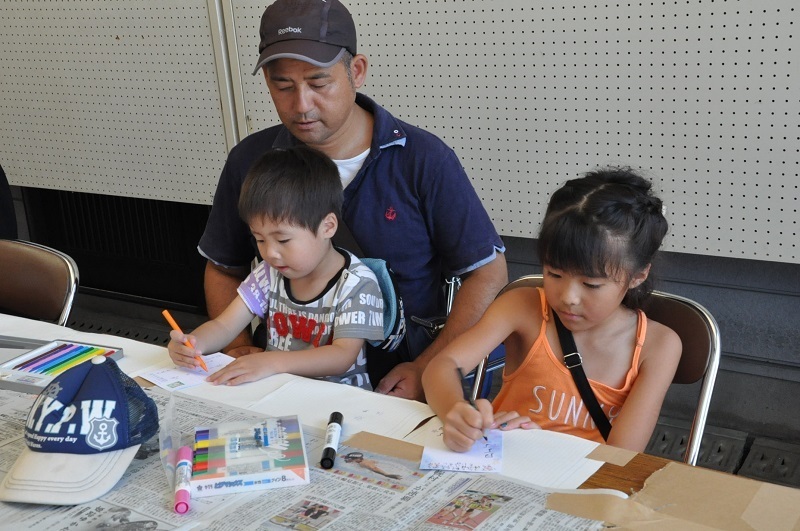 [写真]親子3人で暑中見舞いを作成中。幼い男児はまだ字が書けないので、絵手紙に挑戦