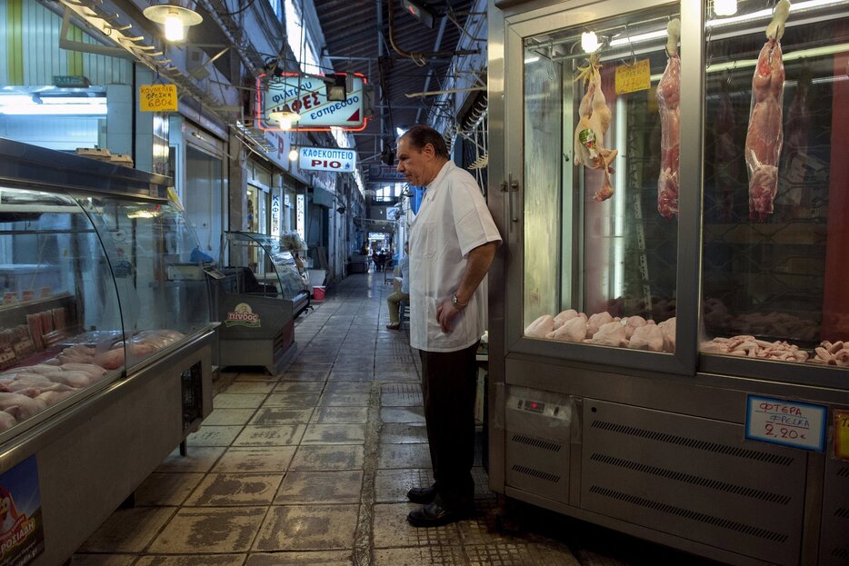 閑散とした店の前に立つ店主。各地で紙幣が不足＝2015年7月2日（写真：ロイター/アフロ）