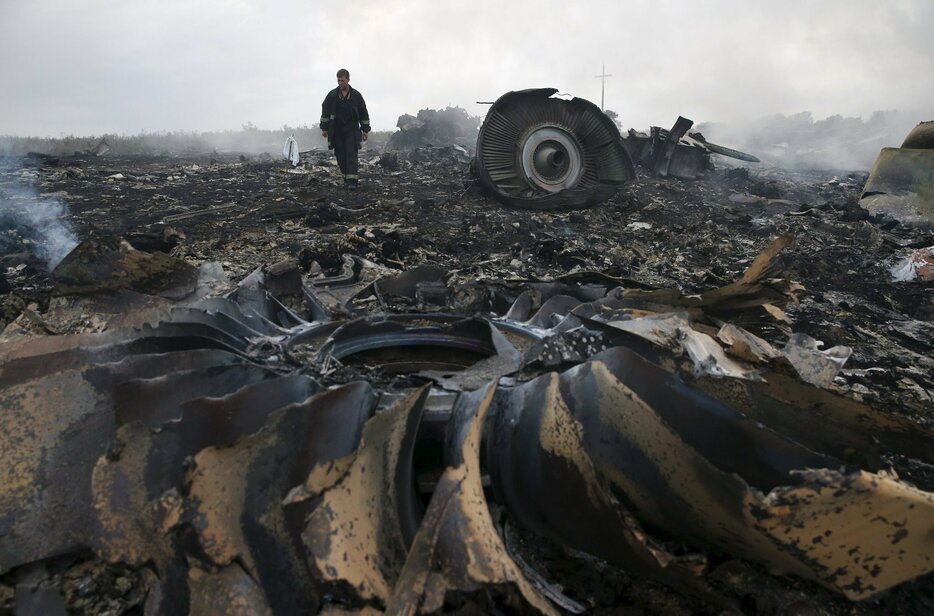 煙が立ちこめる墜落現場を歩く関係者。乗員乗客298人全員が死亡＝2014年7月17日（写真：ロイター/アフロ）