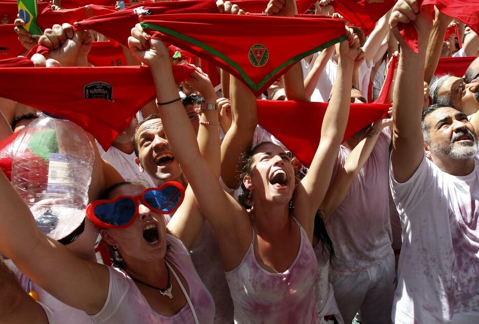 笑顔で赤いスカーフを掲げる女性＝2015年月7月6日（写真：ロイター/アフロ）