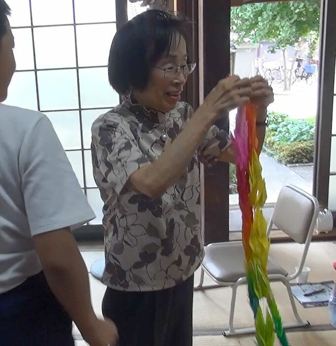 [写真]講演後、小学生の子どもらから千羽鶴を受け取る龍野さん