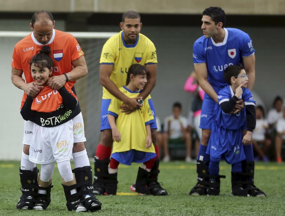 障がいのある子どもとグラウンドに立つブラジル人選手＝2015年7月7日（写真：ロイター/アフロ）