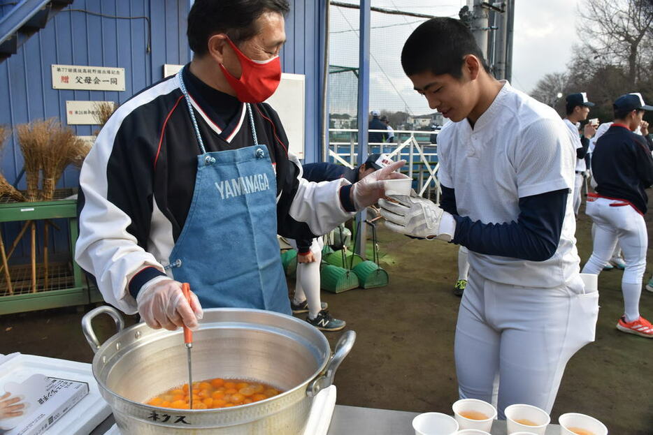 選手らに手作りのキンカンジュースを手渡す車谷さん（左）＝浦和学院高校で２０２２年２月１５日、平本絢子撮影