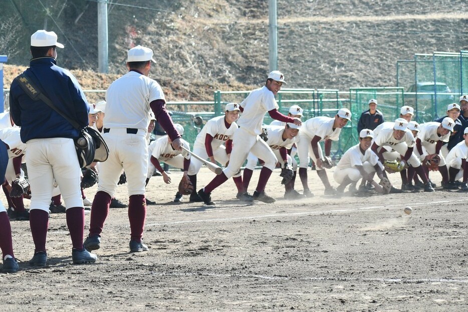 ノック練習で最後の１人を中腰の部員たちが見守る＝高知市の高知高旭グラウンドで２０２２年２月５日午前１０時２８分、小宅洋介撮影