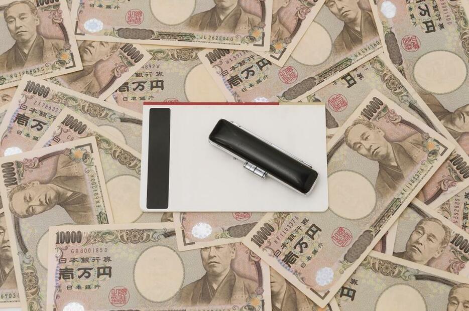 [イメージ]通帳と一万円札。私たちはどうしてもっとお金があったらと思ってしまうのでしょう（写真：アフロ）