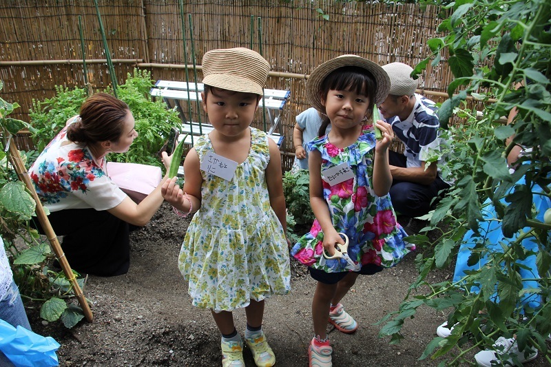 ［写真］ホテル敷地内の自然農園でオクラを収穫して喜ぶ子どもたち＝ホテルプラザオーサカのプラザファームで