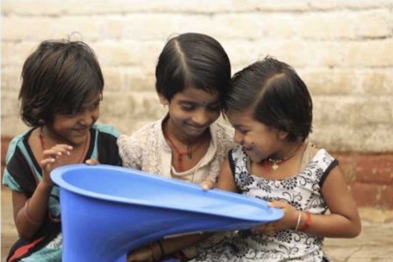 インドで3人の少女がリクシルの開発途上国向け簡易式トイレを手にする様子（リクシル提供）