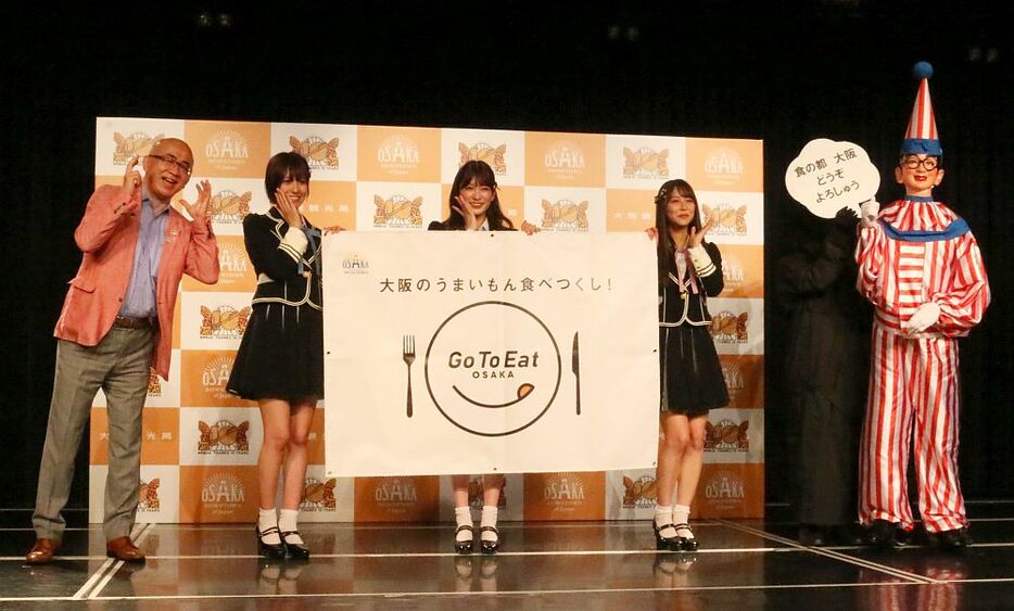 ［写真］大阪観光スペシャルサポーターに就任したNMB48。発表には代表して小嶋花梨、吉田朱里、白間美瑠らが出席。くいだおれ太郎も登場＝18日午前11時50分ごろ大阪市中央区で