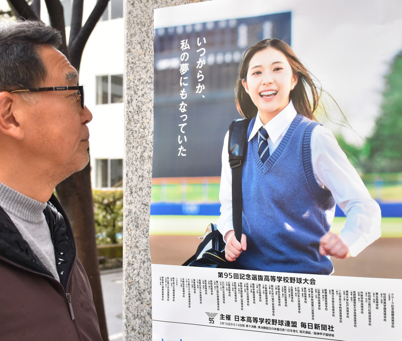 張り出されたセンバツ応援ポスターを眺める男性＝松山市一番町３で、斉藤朋恵撮影
