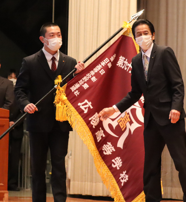 選抜旗を受け取った小林隼翔主将（左）＝広島市安佐南区の広陵高校で２０２３年２月２２日午前８時５７分