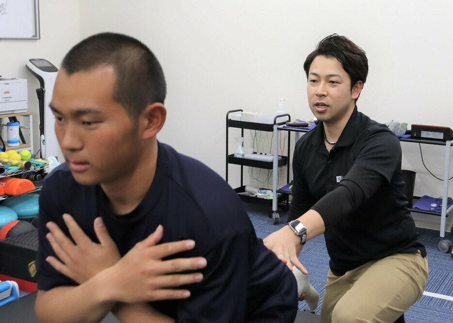 選手に体幹トレーニングの指導をする平山さん（右）