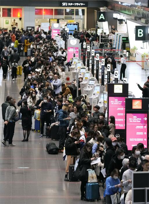 羽田空港の出発ロビーで、航空券の払い戻しなどのため列を作る多くの人たち＝2日午後9時14分