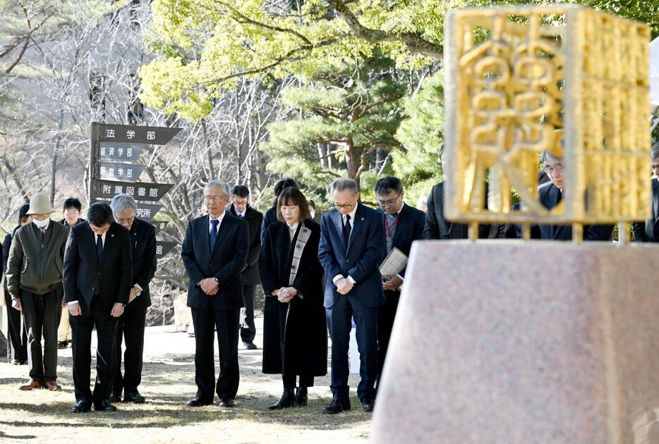 神戸大キャンパスの慰霊碑の前で黙とうする人たち＝17日午後、神戸市灘区