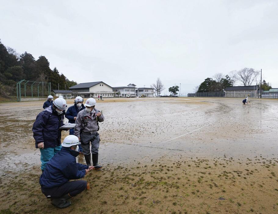 仮設住宅が建設される石川県珠洲市立みさき小学校のグラウンドで行われた測量作業。担当者は「一日でも早く被災された方々に住宅を届けたい」と話した＝12日午後