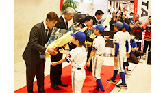 少年スネークの選手たちから花束を受け取るロッテの代表者ら＝30日夕、新石垣空港