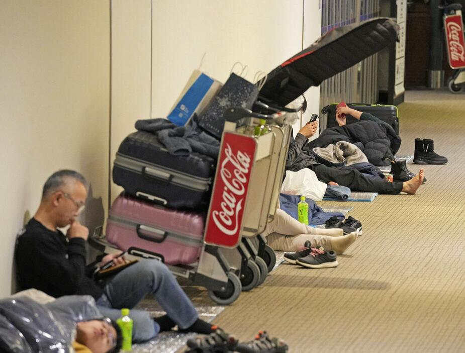 新千歳空港の運営会社が配布した寝袋とマットを利用し、空港内で過ごす人たち＝2日深夜