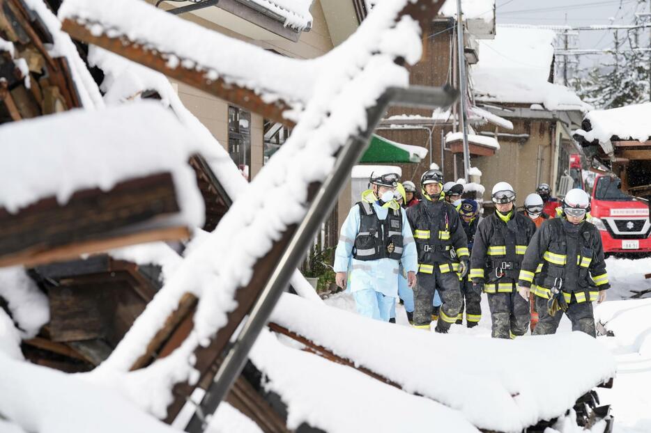 雪に覆われた石川県珠洲市宝立町鵜飼で活動する消防隊員＝8日午前10時30分