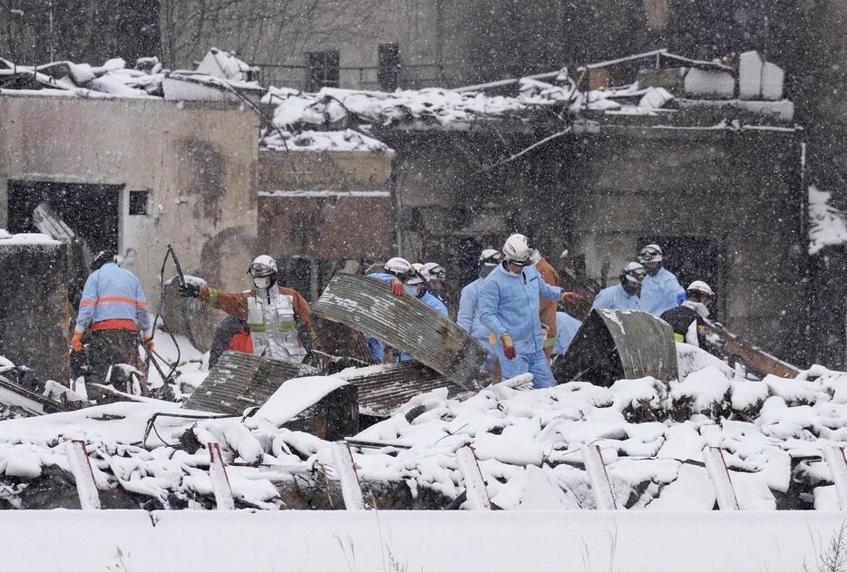 雪に覆われた「輪島朝市」付近で、安否不明者の手掛かりを捜す消防隊員ら＝8日午前8時17分、石川県輪島市