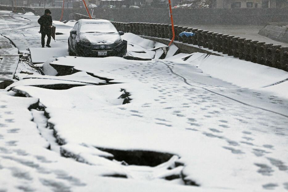 雪が降り積もる、石川県輪島市のひび割れた道路＝13日午後