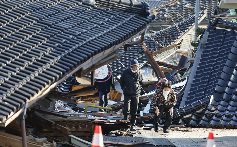 倒壊した家屋の間を歩く女性（81）ら。全壊した家の様子をいっしょに見に来た家族は「まさかこんなことになるとは」と変わり果てた周囲を見つめていた＝4日午前10時26分、石川県珠洲市