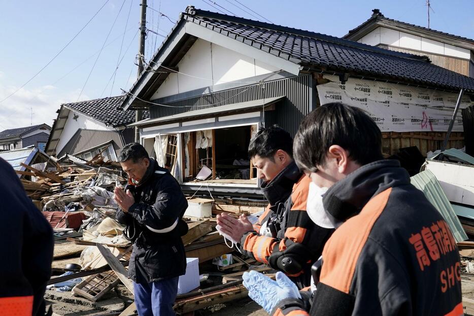 倒壊した建物から犠牲者を運び出し、手を合わせる消防隊員ら＝5日午前10時54分、石川県珠洲市宝立町