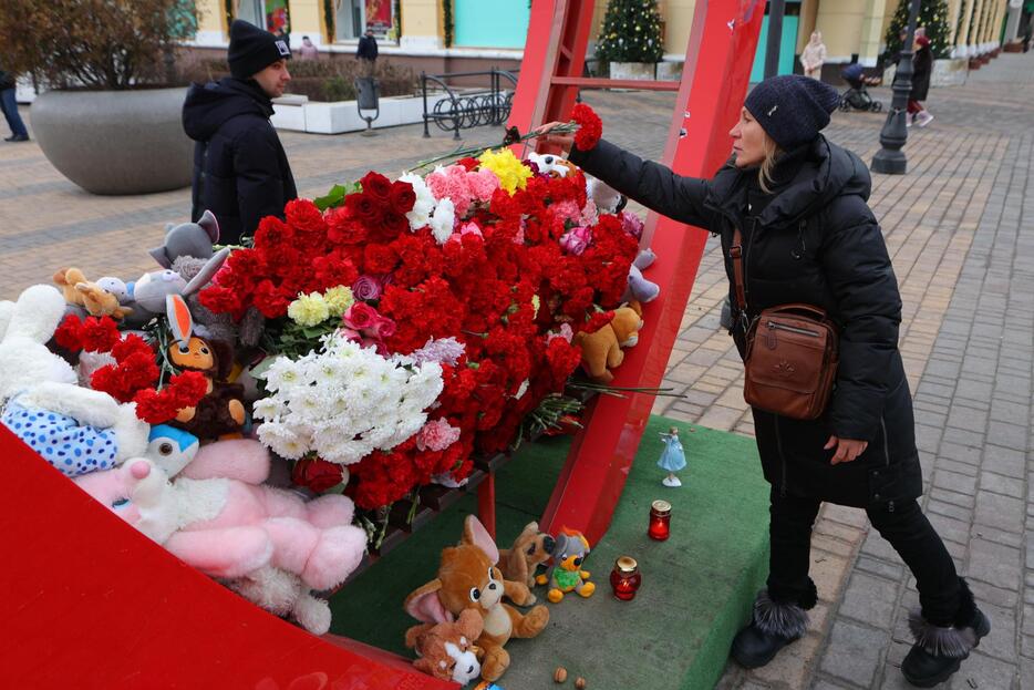 1日、ロシア西部ベルゴロドで、2023年12月30日の砲撃の死者を追悼し献花する女性（タス＝共同）