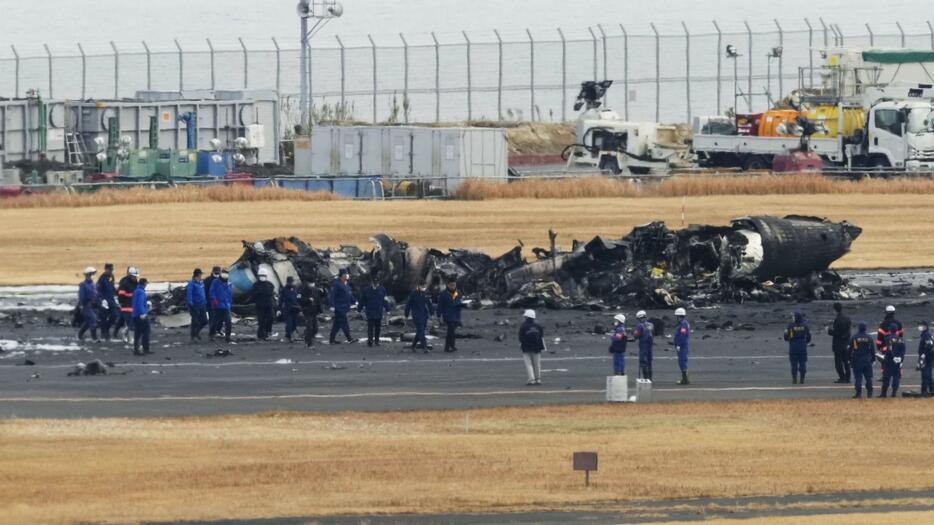 焼け焦げた海上保安庁の航空機周辺に集まる警視庁の捜査員や東京消防庁の隊員ら＝3日、羽田空港