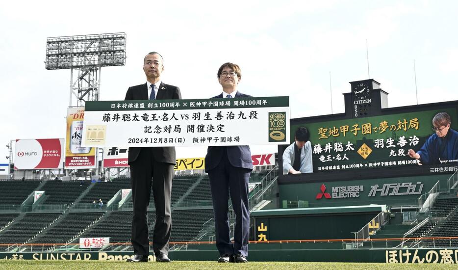 記念対局の開催を発表し、甲子園球場で記念写真に納まる日本将棋連盟会長の羽生善治九段（右）と阪神甲子園球場の向井格郎球場長＝13日午後