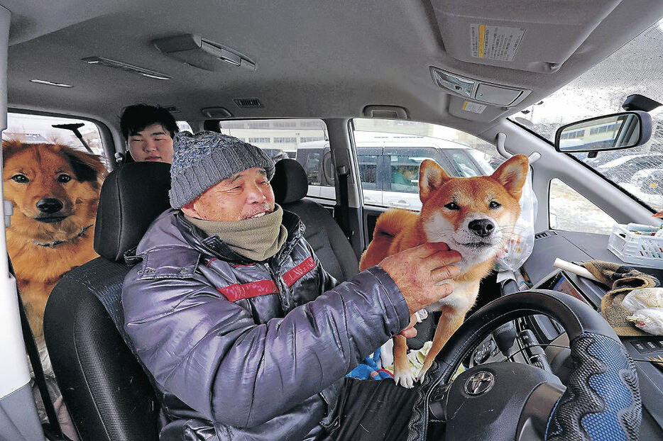 愛犬とともに車中生活を送る山中さん（手前）＝８日午後２時１５分、輪島市鳳至小グラウンド
