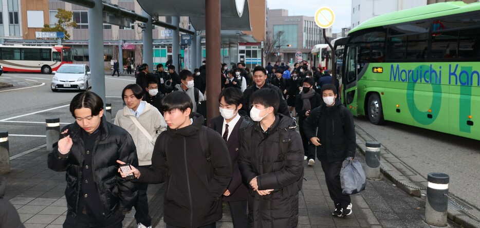 のと鉄道が運行する代替バスを利用し、ＪＲ七尾駅で降りる生徒たち＝２９日午前７時１５分、ＪＲ七尾駅