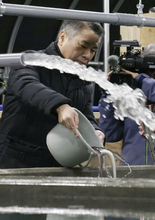 ホワイトデータセンターの養殖施設で、水槽にウナギの稚魚を入れる「池入れ」をする伊地知晋一社長＝12日午前、北海道美唄市