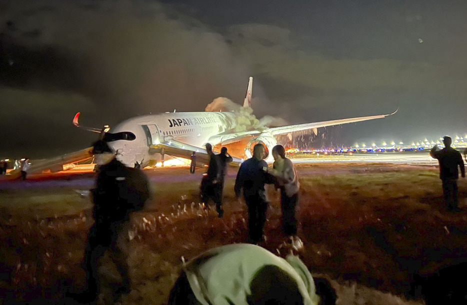 羽田空港の滑走路で炎上する日航516便と逃げる乗客ら＝2日午後（乗客提供）