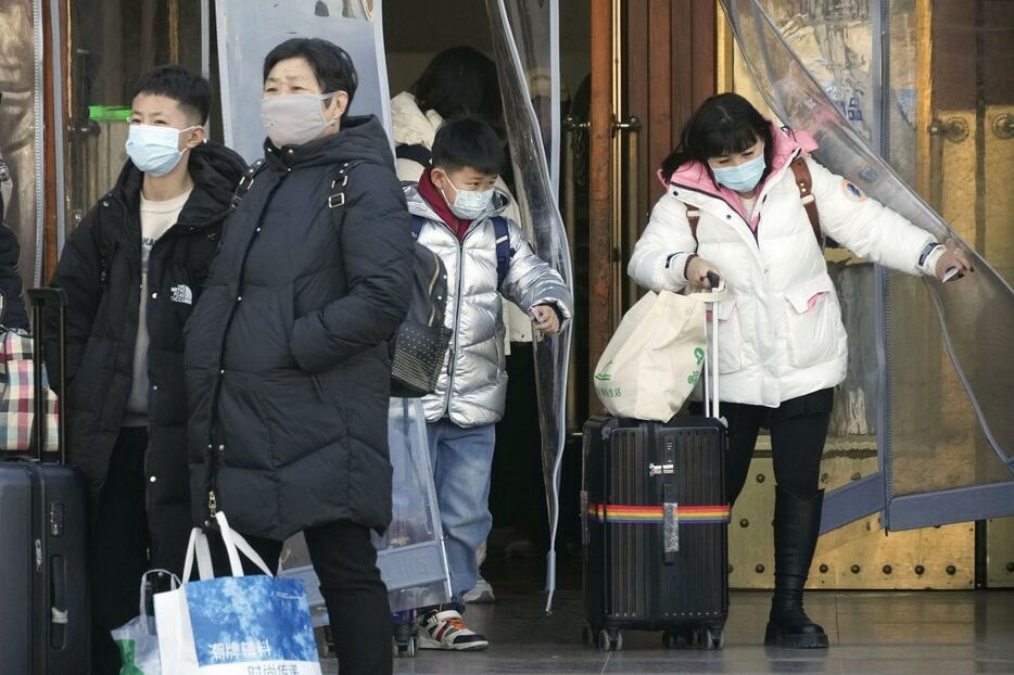 北京駅から出てくるマスク姿の人たち＝26日（共同）