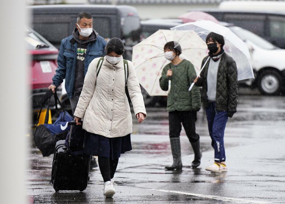 金沢市の施設への集団避難のため、保護者（奥）と集合場所へ向かう中学生＝21日午前、石川県珠洲市