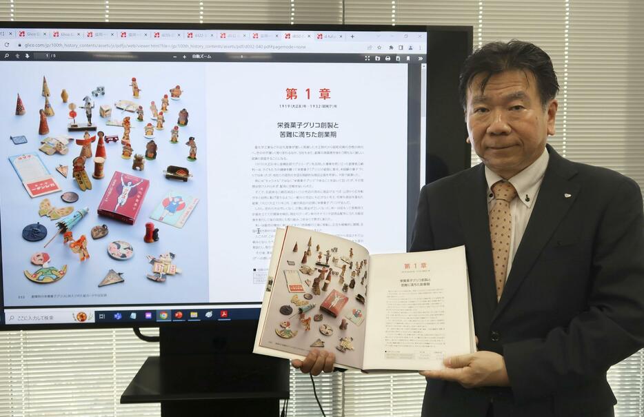 江崎グリコの創立100周年を記念して作成した社史を紹介する同社の清水洋司さん＝22日、大阪市