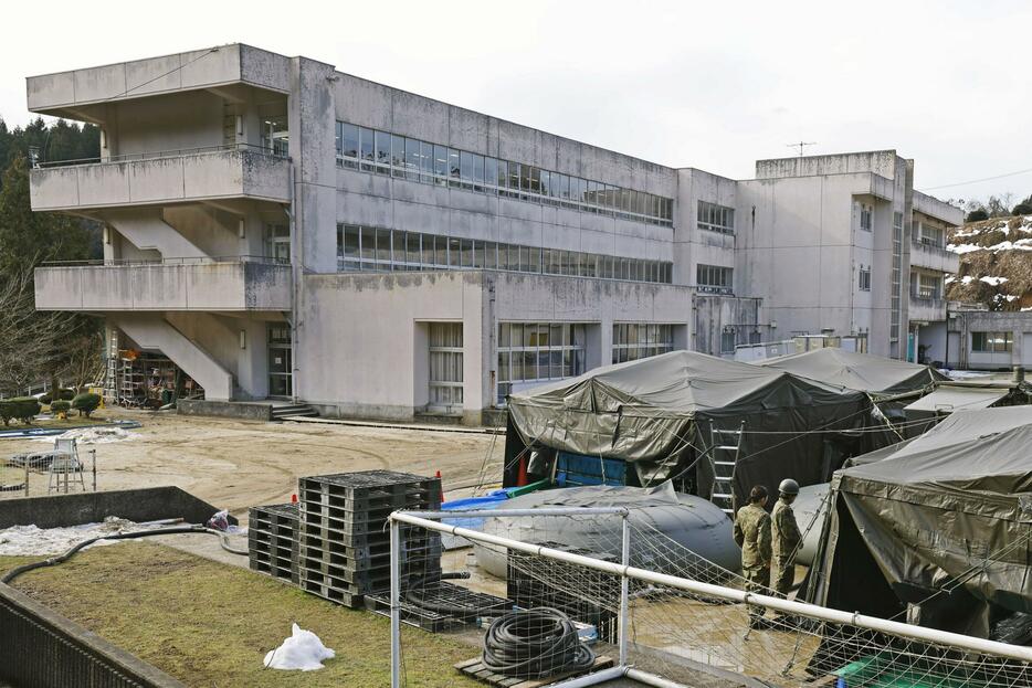 避難所となっている石川県珠洲市立飯田小。手前は自衛隊が設置した臨時浴場＝31日午前