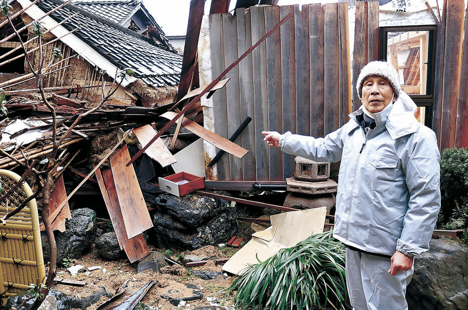 壊れた家を前に、輪島に住み続ける決意を語る由野さん＝１０日午前１１時２０分、輪島市河井町