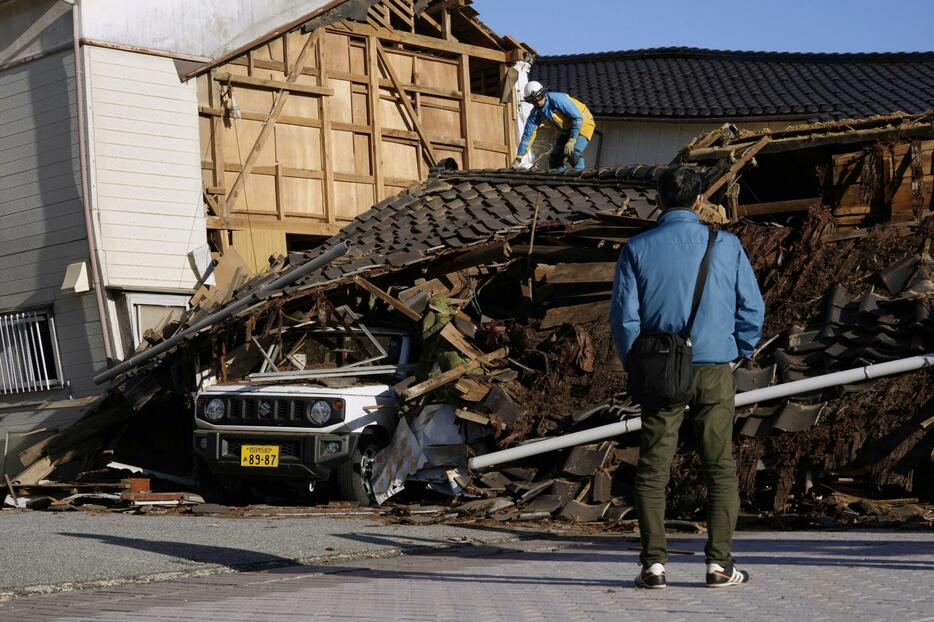 地震で倒壊した住宅の捜索活動を見守る親族の男性＝2日午後2時43分、石川県輪島市