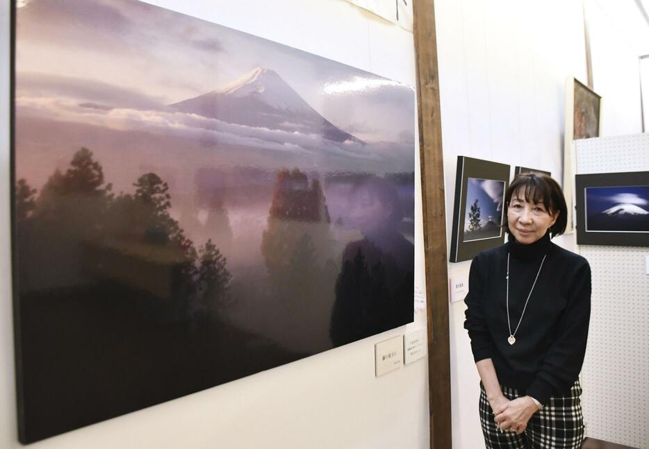 杉浦さんが撮影した富士山の写真の前で、撮影に応じるボランティア団体の代表＝群馬県草津町