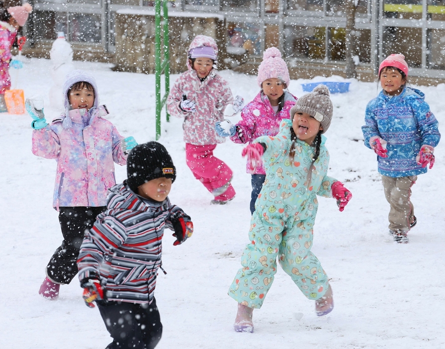 園庭に積もった雪で雪合戦を楽しむ子どもたち