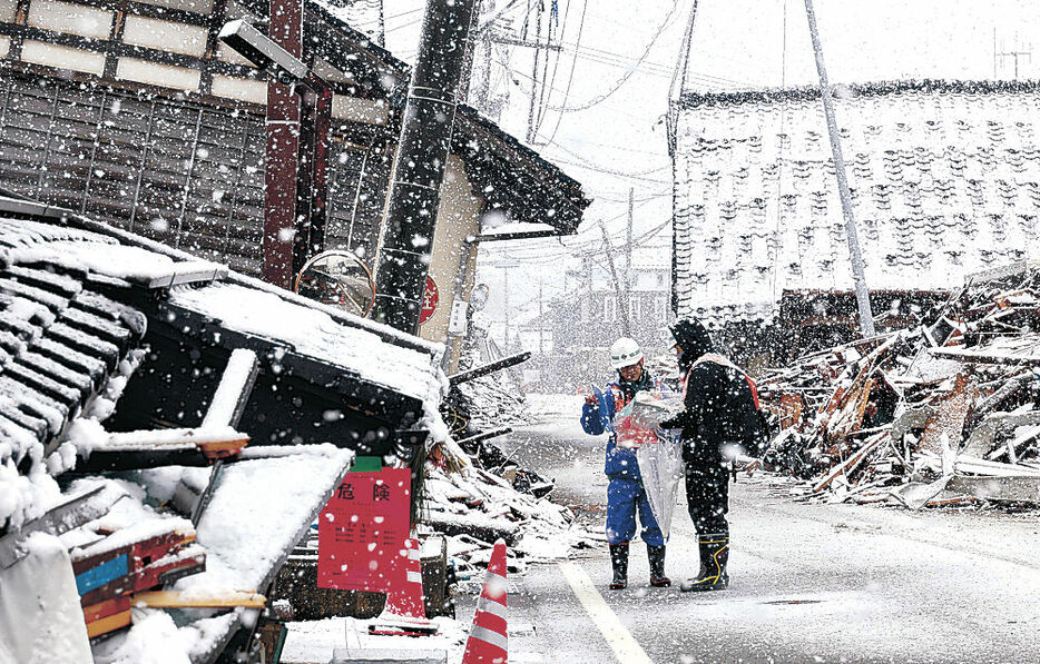 雪の中で倒壊した家屋の状態を調べる応急危険度判定士＝１３日午前９時４０分、珠洲市正院町正院