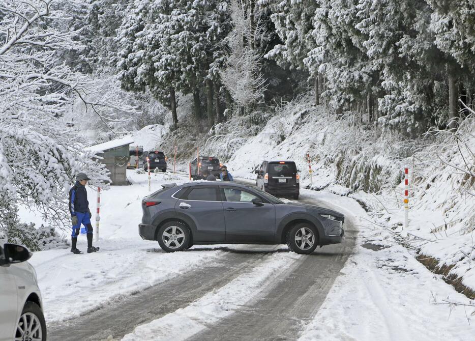 雪が積もり凍結した石川県穴水町の道路で、Uターンする車＝14日午前